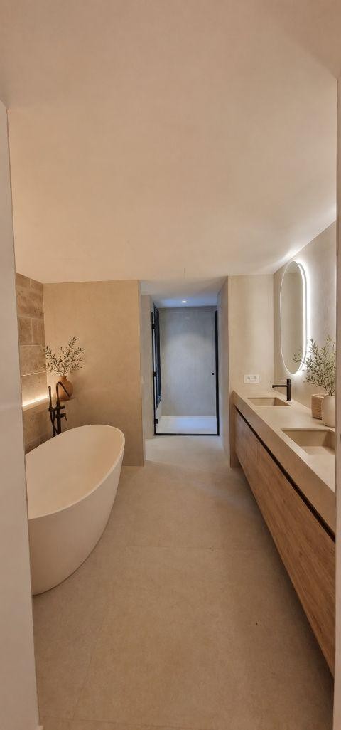 Baño reformado por Ancolem: ducha de obra, iluminación indirecta y acabados cálidos.